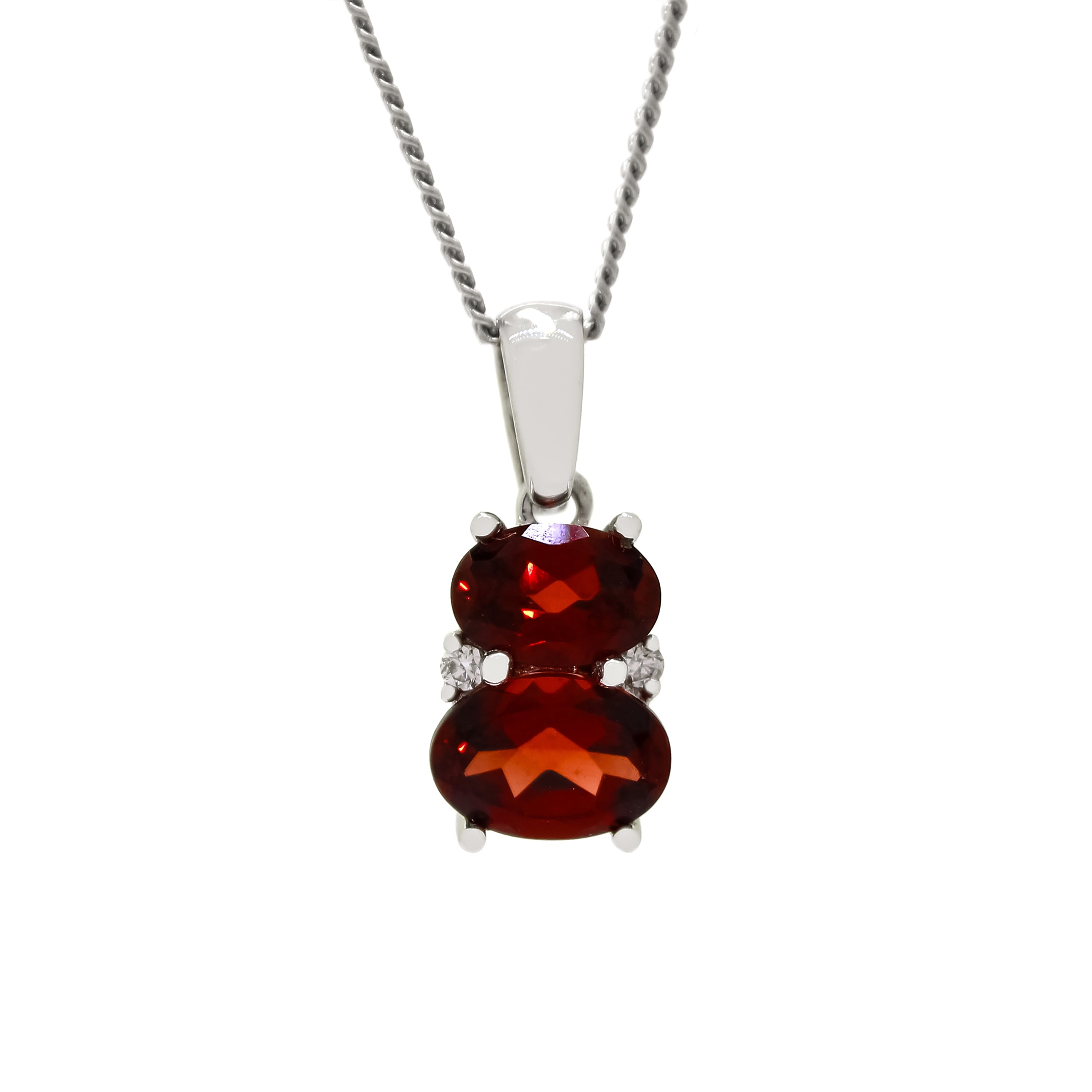 A product photo of a garnet and diamond pendant in 9k white gold sitting on a white background. The pendant is made up of two horizontal oval-shaped red garnet gemstones, the bottom one being 7x5mm and the top being 6x4mm. The spaces between the two stones are filled with one small diamond on either side.