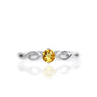 A product photo of an ornate silver ring with a citrine centre stone sitting on a white background. The silver band splits halfway along its length, becoming twisting and serpentine in appearance before meeting on either side of the dazzling orange 3.5mm stone, which is held in place by 4 silver claws.