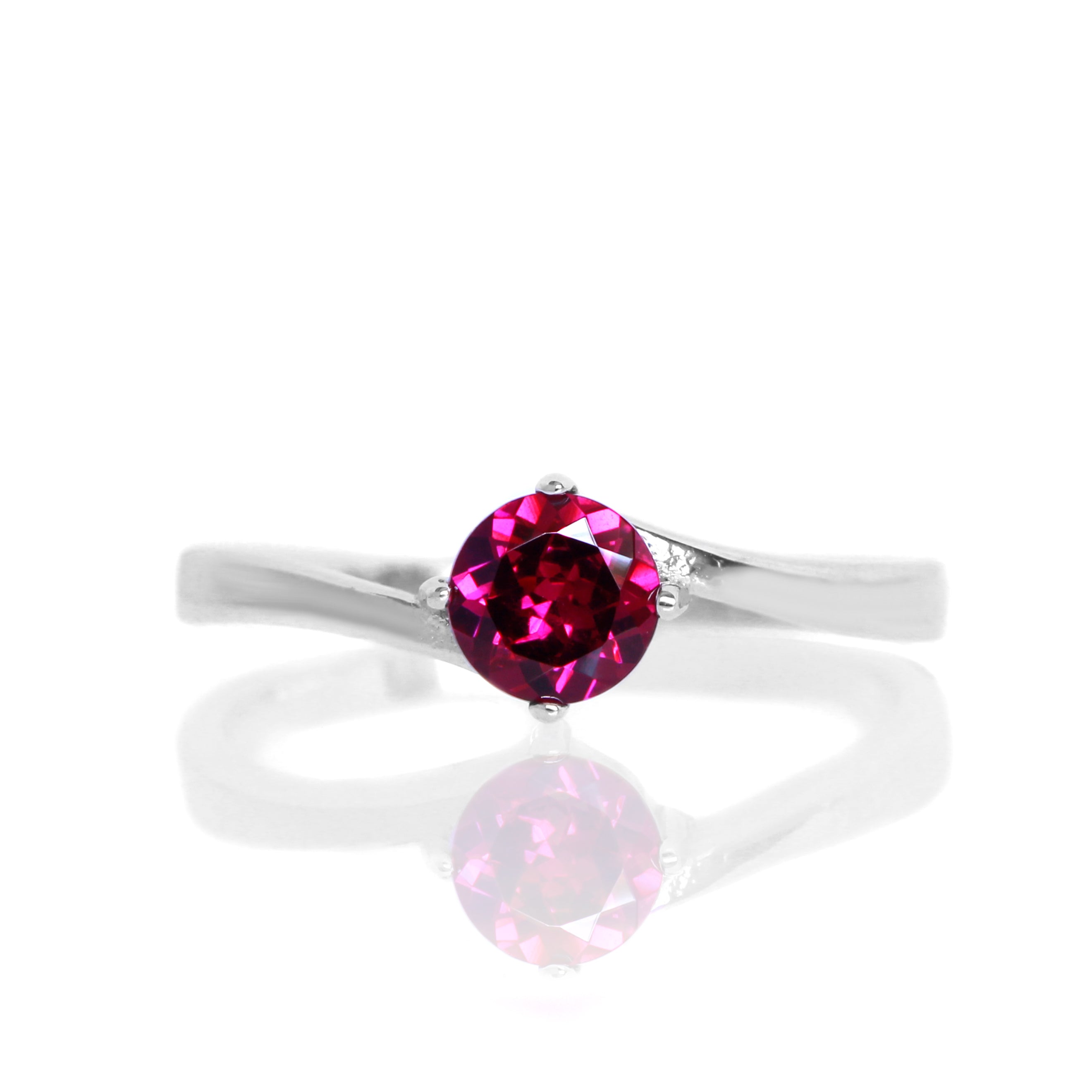 A product photo of a curved-band silver solitaire ring with a rhodalite centre stone sitting on a white background.