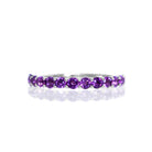 A product photo of a silver eternity band with 13 amethyst stones embedded along its length on a white background.