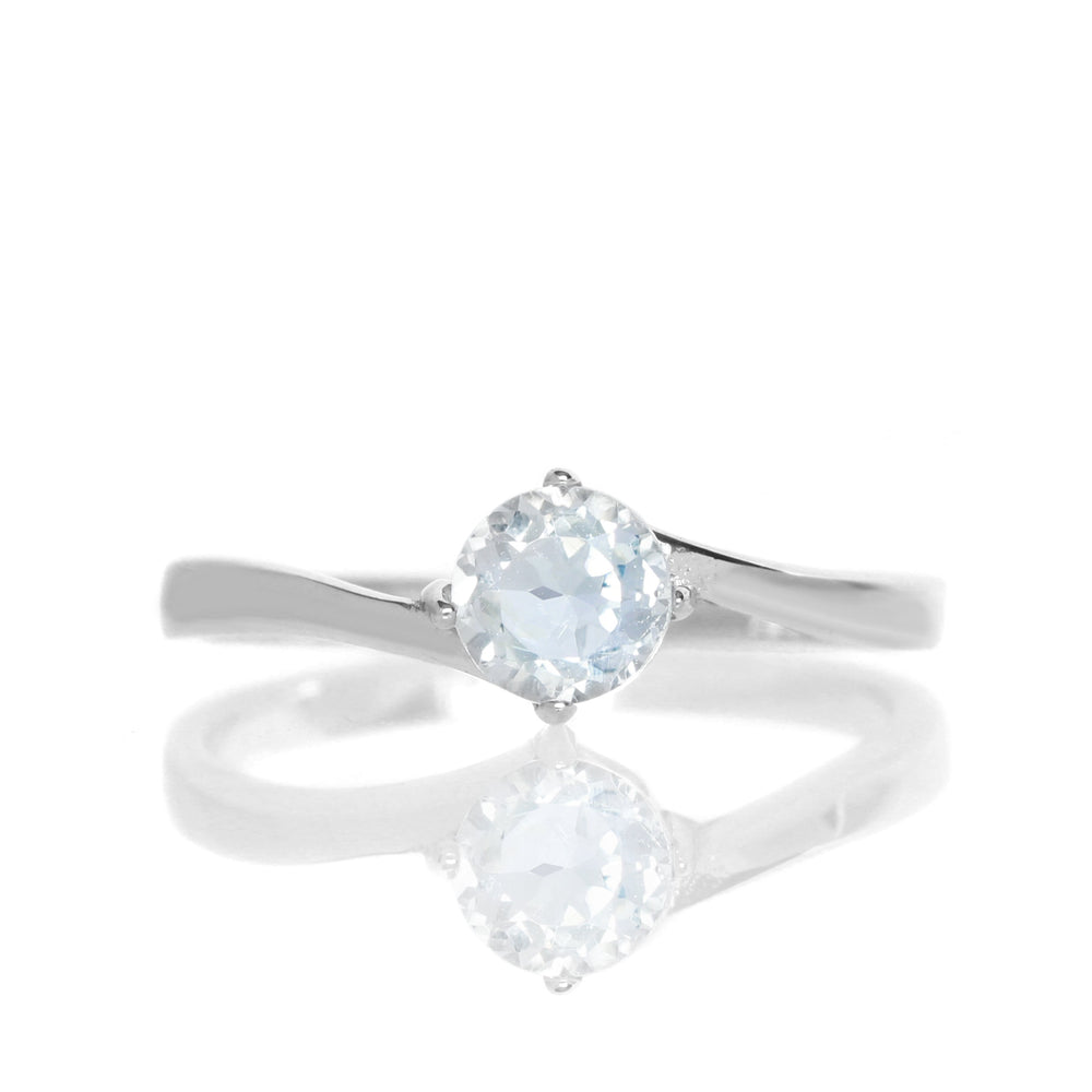 A product photo of a curved-band silver solitaire ring with an ocean blue silver topaz centre stone sitting on a white background.