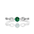 A product photo of an ornate silver ring with a green tourmaline centre stone sitting on a white background. The silver band splits halfway along its length, becoming twisting and serpentine in appearance before meeting on either side of the dazzling green 3.5mm stone, which is held in place by 4 silver claws.