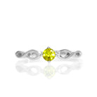 A product photo of an ornate silver ring with a yellow tourmaline centre stone sitting on a white background. The silver band splits halfway along its length, becoming twisting and serpentine in appearance before meeting on either side of the dazzling yellow 3.5mm stone, which is held in place by 4 silver claws.