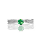 A product photo of a simple silver solitaire ring with a unique band detail and a 4mm round green tourmaline centre stone sitting on a white background. The band is styled to appear as 3 little silver bands, tilted slightly outwards and "overlapping" towards the back of the ring.