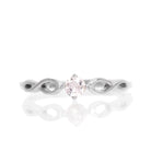 A product photo of an ornate silver ring with a morganite centre stone sitting on a white background. The silver band splits halfway along its length, becoming twisting and serpentine in appearance before meeting on either side of the dazzling pale pink 3.5mm stone, which is held in place by 4 silver claws.