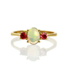 A product photo of a cabochon rainbow opal and pink tourmaline ring in 9 karat yellow gold on a white background. The cabochon cut of the opal allows the viewer to see every angle of the vibrant fire within the translucent stone, while the round pink tourmaline adds a burst of colour.