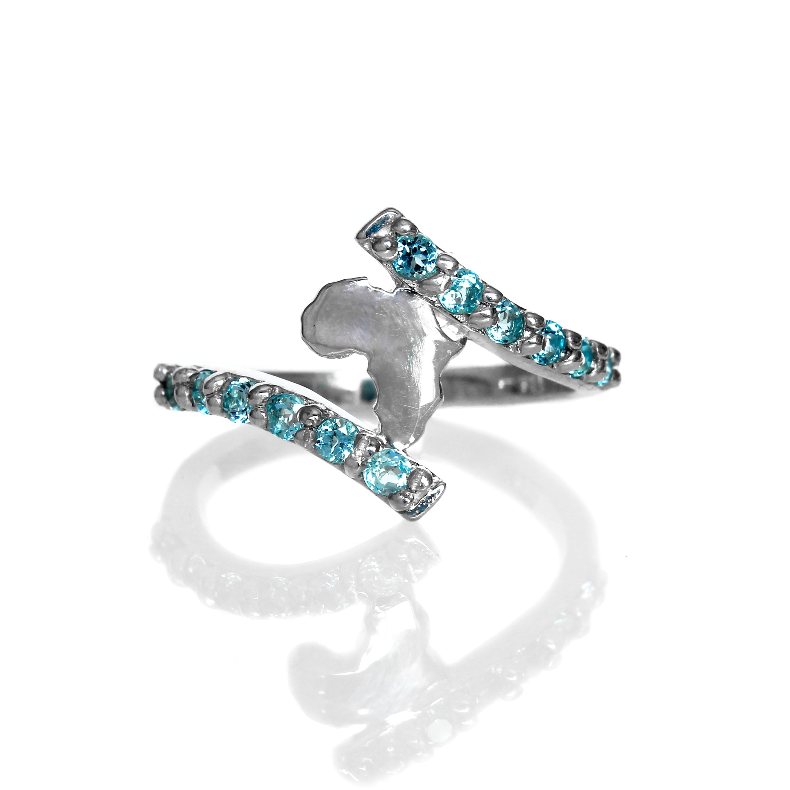 A product photo of a silver ring on a white background. The centre of the silver ring is composed of a cut-out of the African continent, framed at the top and bottom by two swooping lengths of silver, embedded with light blue aquamarine gemstones, that form the ring's band.