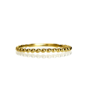 A product photo of a textured yellow 9 karat gold stacking band on a white background. The band's golden surface is punctuated by bead-like detailing.
