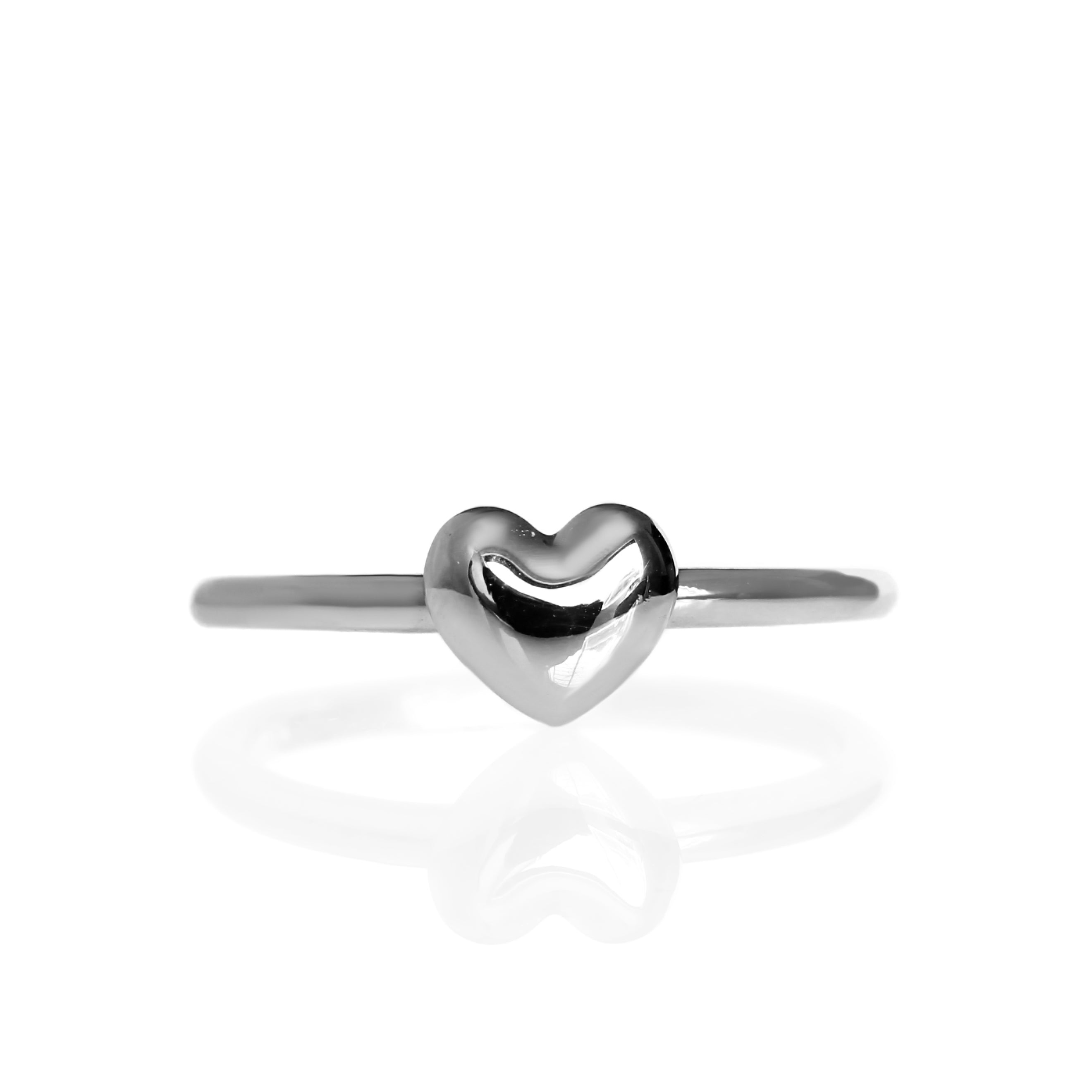 A product photo of a plain white gold heart ring on a white background. The ring's band is thick and rounded, meeting on either side of a small cushioned heart made of solid gold.