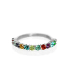 A silver multi-gemstone eternity ring sitting on a white reflective background. The ring is made up of 13 2.5mm round-cut semi-precious gemstones in a rainbow of colours.