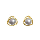 A product photo of a pair of 8mm steel grey pearl earring studs with ornate, twisted 9 karat yellow gold backs on a white background.