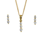 A product photo of a women's jewellery gift set in 9ct yellow gold and sparkling moissanite suspended against a white background. The yellow gold moissanite earrrings, each made up of 3 stones stacked vertically, descending from smallest to largest, sit on either side of a pendant of the same design suspended by a golden chain.